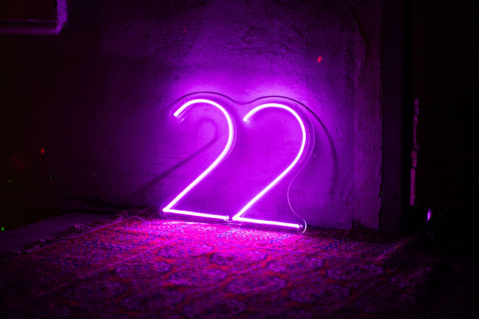 Neon-Schriftzug 22 in Lila an einer dunklen Wand